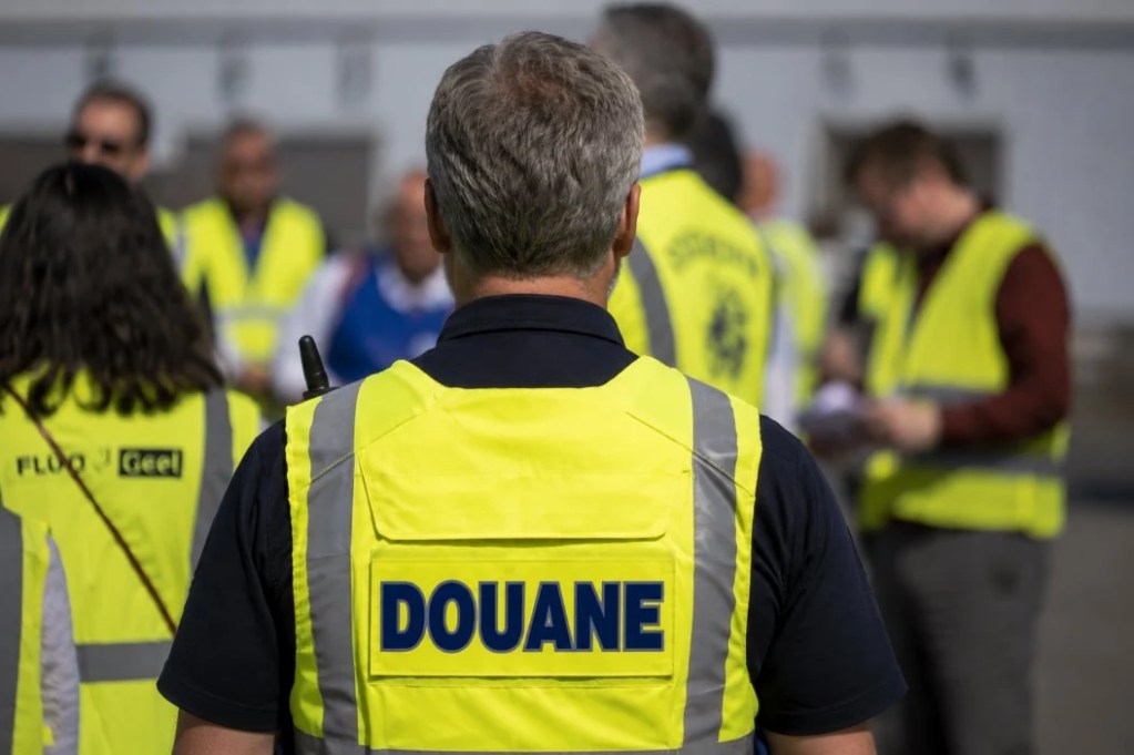 Customs officer in a high-visibility vest checking containers at a port terminal